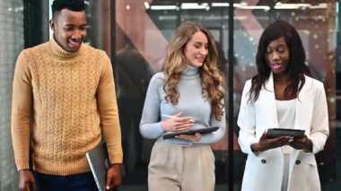 Ofisteki çok ırklı işçiler tablet kullanarak iş konuşuyorlar.