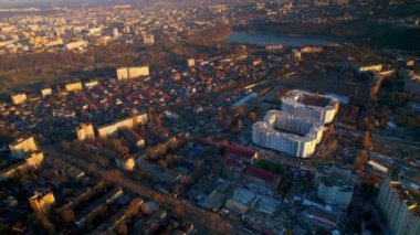 Chisinau 'nun günbatımında Moldova' da hava aracı görüntüsü. Birden fazla bina ve yol olan şehir manzarası, göl kenarına park etmek.