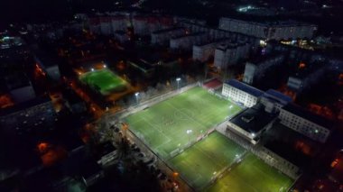 Geceleri Chisinau 'nun hava aracı görüntüsü, Moldova. Şehir manzarası, aydınlık bir stadyumda futbol oynayan insanlar, etrafındaki binalar.