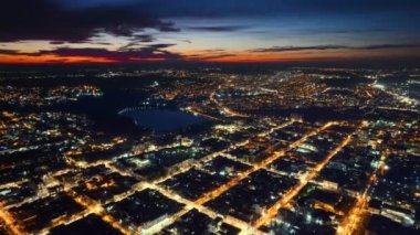 Chisinau 'nun gün batımında Moldova' daki hava aracı görüntüsü. Birden fazla konut binası olan şehir manzarası, göllü park, hareket halindeki arabalar, aydınlatma