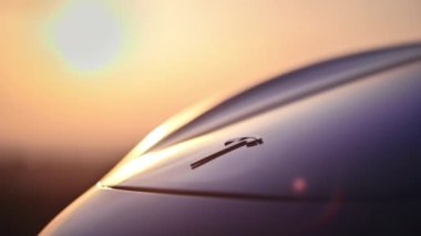 CHISINAU, MOLDOVA - Şubat 2023: Arka planda Güneş üzerinde batan, park halindeki Tesla Model 3 'ün ön logosunun yakın görüntüsü