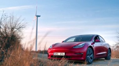 CHISINAU, MOLDOVA - Şubat 2023: park halindeki Tesla Model 3. Arka planda rüzgar türbini