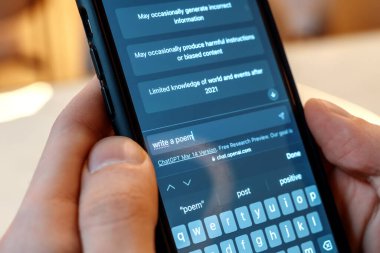 İçinde yapay zeka sohbeti olan bir akıllı telefon tutan kişi. Kullanıcı sohbet robotundan şiir yazmasını istiyor