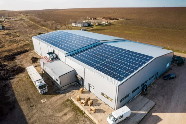 Doğadaki bir imalat binasının çatısındaki çoklu güneş panellerinin insansız hava aracı görüntüsü. Ekoloji teması