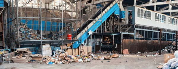Panoramic view of interior of a waste sorting plant. Garbage everywhere, special tools