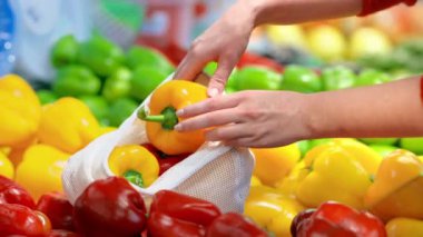 Tekrar kullanılabilir bir torbada dolmalık biber toplayan bir kadın. Ekoloji ve Dünya Günü teması