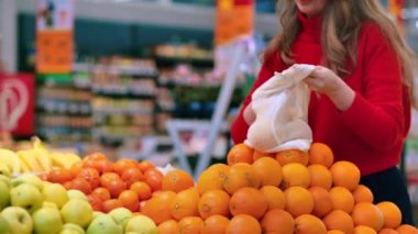 Mağazadaki portakal toplayan bir kadın. Ekoloji ve Dünya Günü teması