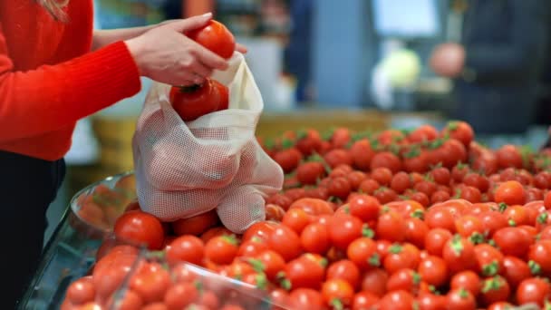 女人在商店里的一个可重复使用的袋子里捡西红柿 生态与地球日 — 图库视频影像