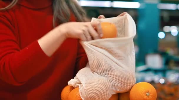 女人在商店里的可重复使用的袋子里采摘橙子 生态与地球日 — 图库视频影像