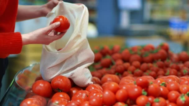 店内の再利用可能な袋にトマトを摘む女性 生態学と地球の日のテーマ — ストック動画