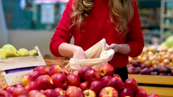 女人在商店里的可重复使用的袋子里摘苹果 生态与地球日 — 图库视频影像