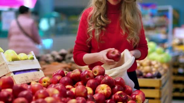 店内の再利用可能な袋にりんごを選ぶ女性 生態学と地球の日のテーマ — ストック動画