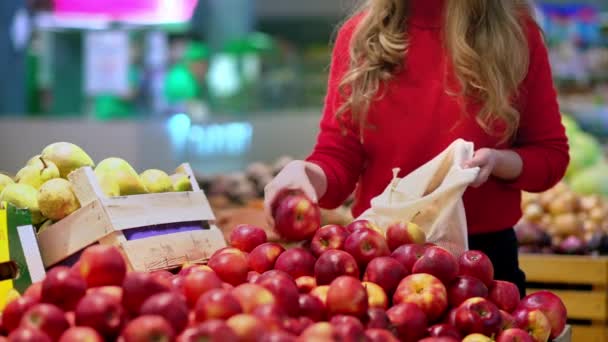 女人在商店里的可重复使用的袋子里摘苹果 生态与地球日 — 图库视频影像