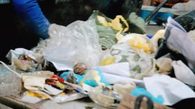 Atık tasnif tesisinde çöp taşıyıcı bant üzerinde çalışan bir çalışan