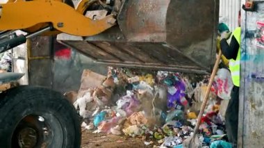 Çöpleri atık tasnif tesisine boşaltan bir kazıcı. Yavaş çekim