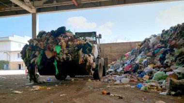 CHISINAU, MOLDOVA - Mart 2023: İşçiler ve bir kazıcı atık tasnif tesisinde bir taşıyıcı bandına çöp yüklüyor