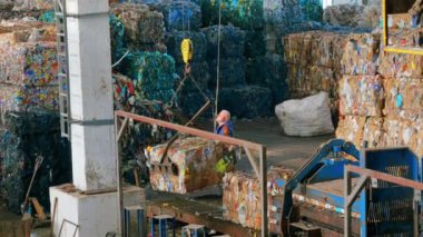 CHISINAU, MOLDOVA - Mart 2023: Bir çalışan atık toplama tesisinde bir yükleyici kullanarak sıkıştırılmış çöp yığıyor