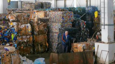 CHISINAU, MOLDOVA - Mart 2023: Atık tesisinde sıkıştırılmış çöp küpü taşıyan bir çalışan