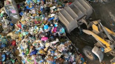 CHISINAU, MOLDOVA - Mart 2023: Atık ayıklama tesisinde büyük bir çöp yığınından çöp toplayan bir kazıcının insansız hava aracı görüntüsü. Yavaş çekim