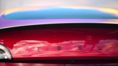 CHISINAU, MOLDOVA - Mart 2023: arkadaki kırmızı Tesla Model 3 logosunu yakın görüş. Yavaş çekim