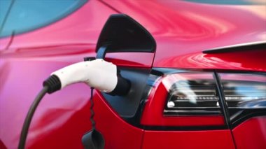 CHISINAU, MOLDOVA - Mart 2023: Kırmızı Tesla Model 3 şarj yakın görüş. Yavaş çekim