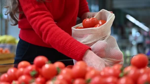 女人在商店里的一个可重复使用的袋子里捡西红柿 生态学与地球日 慢动作 — 图库视频影像