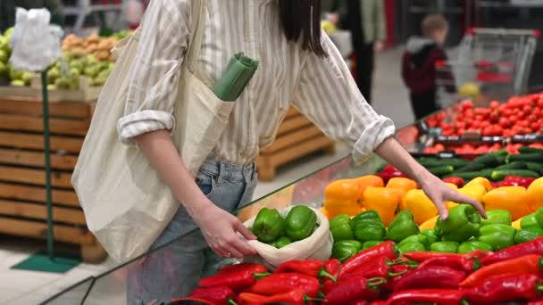 女人在商店里的一个可重复使用的袋子里捡甜椒 生态学与地球日 慢动作 — 图库视频影像