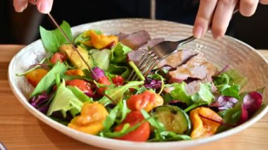 Restoranda biftek ve sebze yiyen bir kadın.