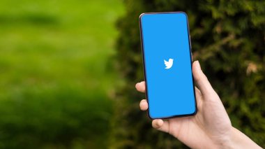 CHISINAU, MOLDOVA - Nisan 2023: Twitter 'ı açık olan bir akıllı telefonu elinde tutan kişinin görüntüsü. Arkaplanda yeşillik