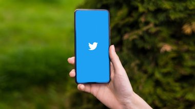 CHISINAU, MOLDOVA - Nisan 2023: Twitter logosu olan akıllı telefonu elinde tutan kişinin görüntüsü. Arkaplanda yeşillik