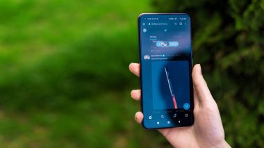 CHISINAU, MOLDOVA - Nisan 2023: Twitter 'ı açık olan akıllı telefonu elinde tutan bir adamın görüntüsü. Arkaplanda yeşillik