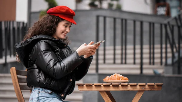 Uma Jovem Blogueira Sorridente Influenciadora Chapéu Vermelho Tirar Fotos Croissant — Fotografia de Stock