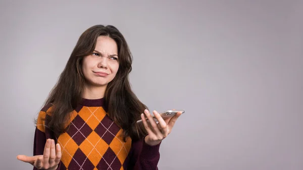 Молодая Сомневающаяся Женщина Разговаривает Телефону Сером Фоне — стоковое фото