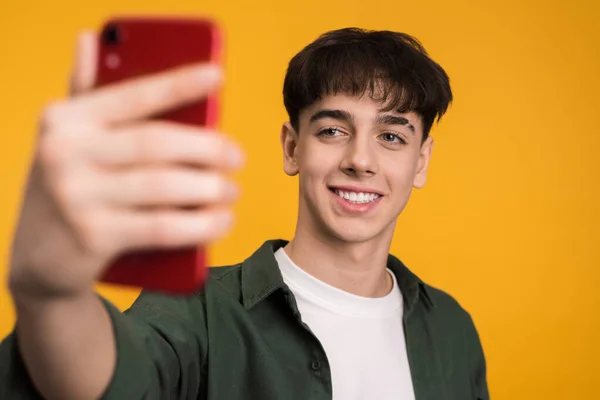 stock image Young man talking while filming himself on the phone on a yellow background