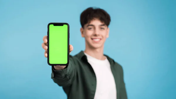 Ung Man Ler Och Visar Sin Telefon Med Grön Skärm — Stockfoto