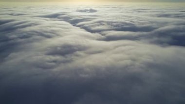 Yükselen bulutların üzerinde uçan bir dronun hava görüntüsü, parlak güneş