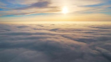 Hareket eden yemyeşil bulutların üzerinde uçan bir dronun güneş ışığını yansıtan zaman ayarlı görüntüsü.