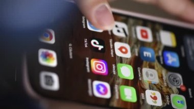 CHISINAU, MOLDOVA - Nisan 2023: TikTok 'u akıllı telefondan açan ve kaydırmaya başlayan bir kadının yakın görüntüsü. Diğer uygulamalarla ana ekran