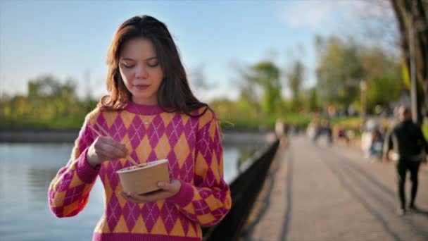 Vista Uma Mulher Comendo Uma Tigela Usando Pauzinhos Parque Pessoas — Vídeo de Stock