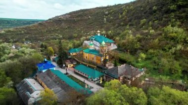 Moldova 'daki Sahra Manastırı' nın insansız hava aracı görüntüsü. Vadideki yemyeşil ormanlarla kaplı kiliseleri olan bir manastır.