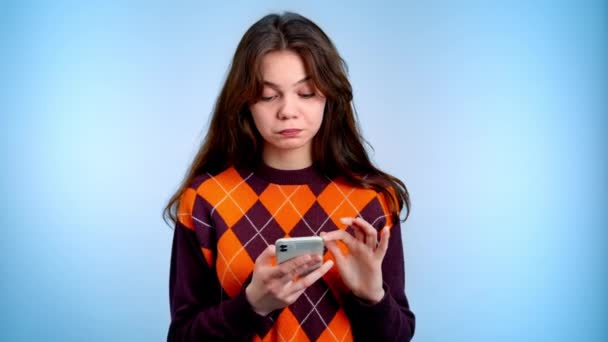 年轻女人用手机在灰色背景下表现出反光的情感 — 图库视频影像