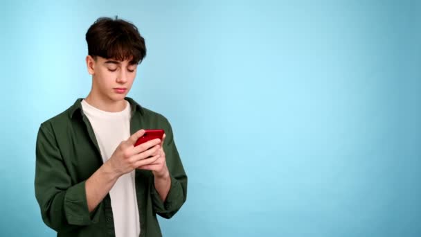Молодой Человек Использует Свой Телефон Синем Фоне — стоковое видео