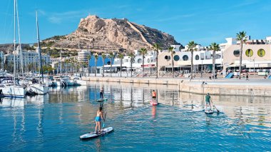 ALICANTE, İSPAN - 2023 NİSAN: Santa Barbara Kalesi yakınlarındaki limanda insanlar ayakta sörf yapıyor