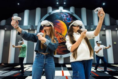 Bir grup arkadaş VR ile etkileşimde. Sanal Gerçekliği kullanarak arenada oynayan bir grup genç.
