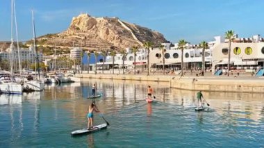 ALICANTE, İSPAN - 2023 NİSAN: Santa Barbara Kalesi yakınlarındaki limanda insanlar ayakta sörf yapıyor