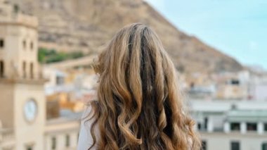 Beyaz kadın, İspanya 'daki Alicante kasabasının panoramik manzarasını izliyor. Arka planda belediye binası