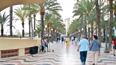 ALICANTE, İspanya - 24 Nisan 2023 Sokakta yürüyen insanlar Palmiye ağaçları ve detaylı kaldırımlarla Espana 'da