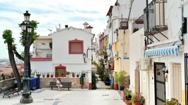 Alicante, İspanya 'da evleri olan bir sokak. Bankta oturan kadın