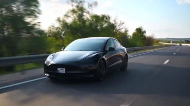 CHISINAU, MOLDOVA - MAYIS, 2023: Otoyoldaki hareketli siyah Tesla Model 3 'ün ön görüntüsü. Arkaplanda doğa