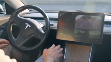 CHISINAU, MOLDOVA - Mayıs 2023: Otomatik pilotta bir Tesla Model 3 'ün iç görüntüsü. Şoför direksiyona dokunmuyor.